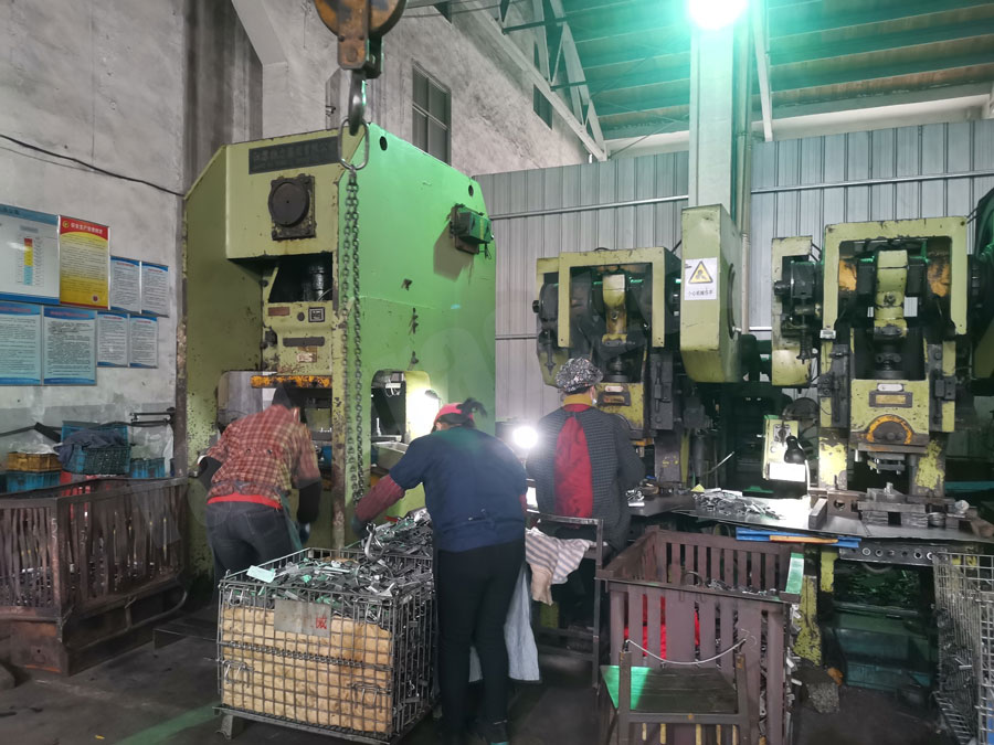 Workers operating presses for rail fastening components